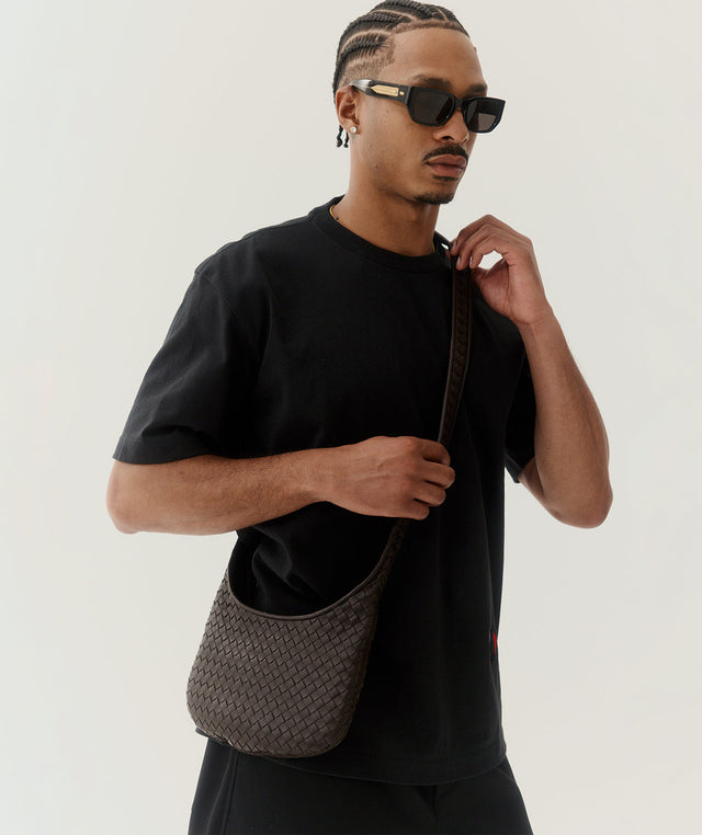 Man holding a Bottega Veneta shoulder bag wearing a black T-shirt 