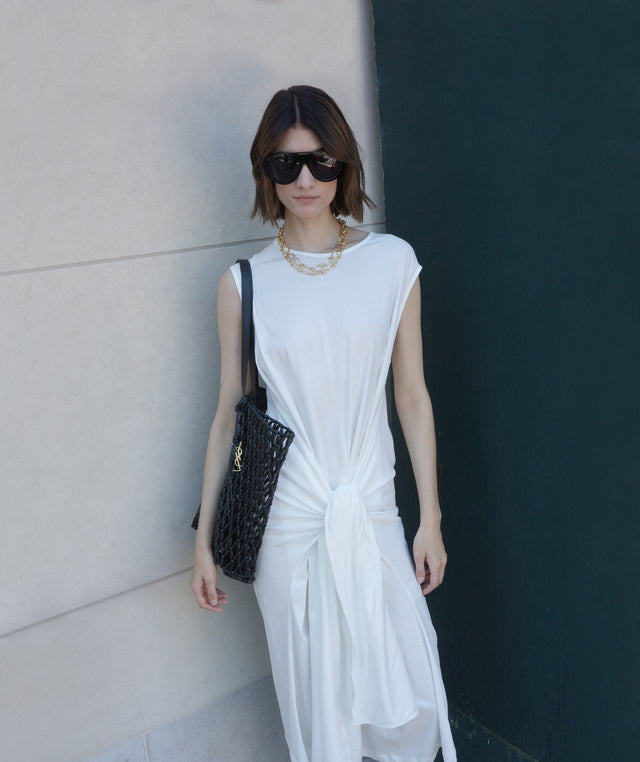 Woman in a white dress by Toteme holding a beaded shopping bag by Saint Laurent 