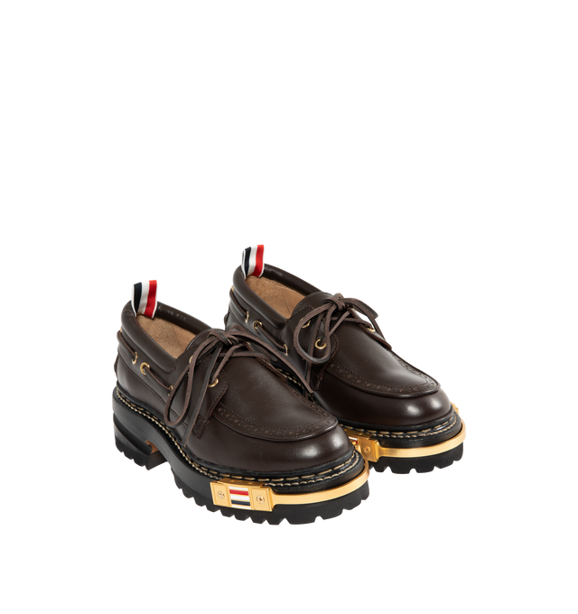 Image 2 of 4 - BROWN - THOM BROWNE Vitello Lug Boat Shoes featuring grained calfskin boat shoes, bumper hardware at toe with enameled stripes, perforated detailing at moc toe, lace-up closure, padded collar, serrated edge at sides and heel counter, tricolor grosgrain pull-loop at heel collar, buffed calfskin lining, stacked leather midsole and heel and treaded rubber sole. Heel: H2". Calfskin. Sole: rubber. Made in Italy. 
