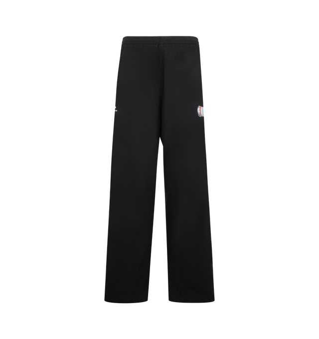 Image 1 of 4 - BLACK - BALENCIAGA NBA Tracksuit Pants featuring technical polyamide, contrasting yokes, mid-waist, elasticated waistband, 2 zipped slash pockets, loop sports icon artwork embroidered on right leg and NBA artwork embroidered on left leg. 100% polyamide. Lining: 100% polyester. Made in Portugal.