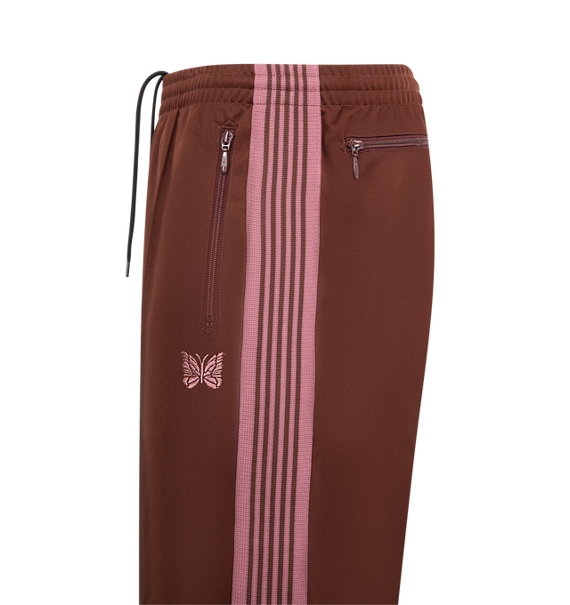Image 3 of 3 - BROWN - NEEDLES Track Pant featuring signature design details, striped trims, an embroidered butterfly logo, elastic waist with drawstring and zipped pockets. 100% polyester. Made in Japan.  