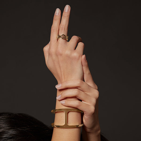 Hand wearing a gold ring and bracelet by Hoorsenbuhs