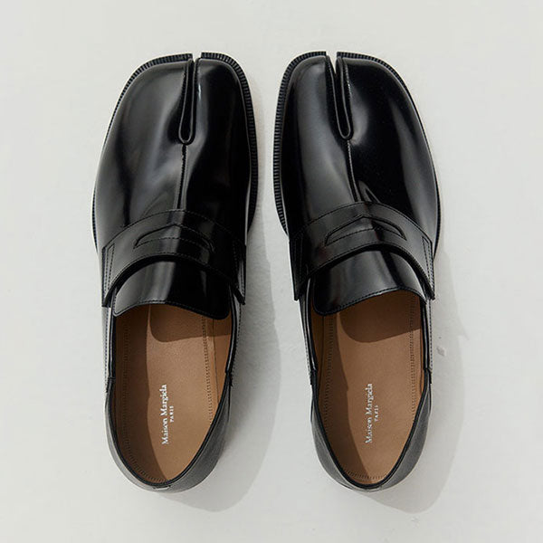 Pair of Maison Margiela black Tabi loafers on a light gray background