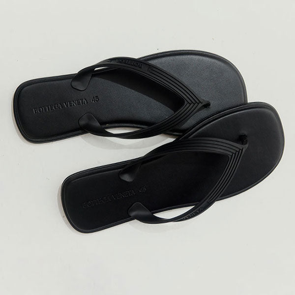 Black Bottega Veneta leather flip-flops with brand logo on a light gray background