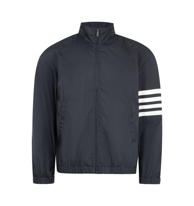 Image 1 of 3 - NAVY - THOM BROWNE Shiny Ripstop Raglan Track Jacket featuring front hidden zip closure, stand collar, welt hand pockets, interior snap pocket, raglan sleeves, elasticated cuffs and hem, 4-bar detailing, name tag appliqu and signature striped grosgrain loop tab. 81% polyamide, 19% polyester. Made in Italy.