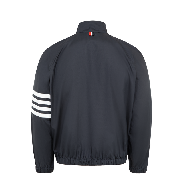 Image 2 of 3 - NAVY - THOM BROWNE Shiny Ripstop Raglan Track Jacket featuring front hidden zip closure, stand collar, welt hand pockets, interior snap pocket, raglan sleeves, elasticated cuffs and hem, 4-bar detailing, name tag appliqu and signature striped grosgrain loop tab. 81% polyamide, 19% polyester. Made in Italy.