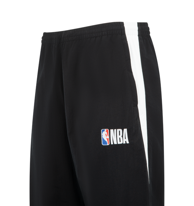 Image 4 of 4 - BLACK - BALENCIAGA NBA Tracksuit Pants featuring technical polyamide, contrasting yokes, mid-waist, elasticated waistband, 2 zipped slash pockets, loop sports icon artwork embroidered on right leg and NBA artwork embroidered on left leg. 100% polyamide. Lining: 100% polyester. Made in Portugal.