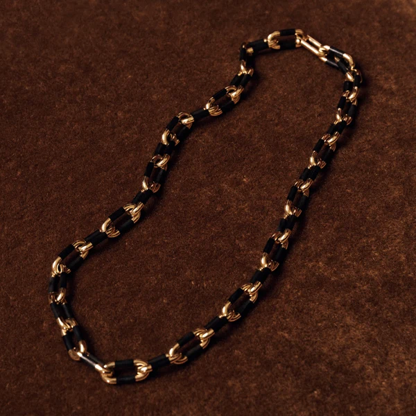 Sidney Garber gold and black chain necklace with alternating polished gold links and black rectangular links, displayed on a textured brown background.