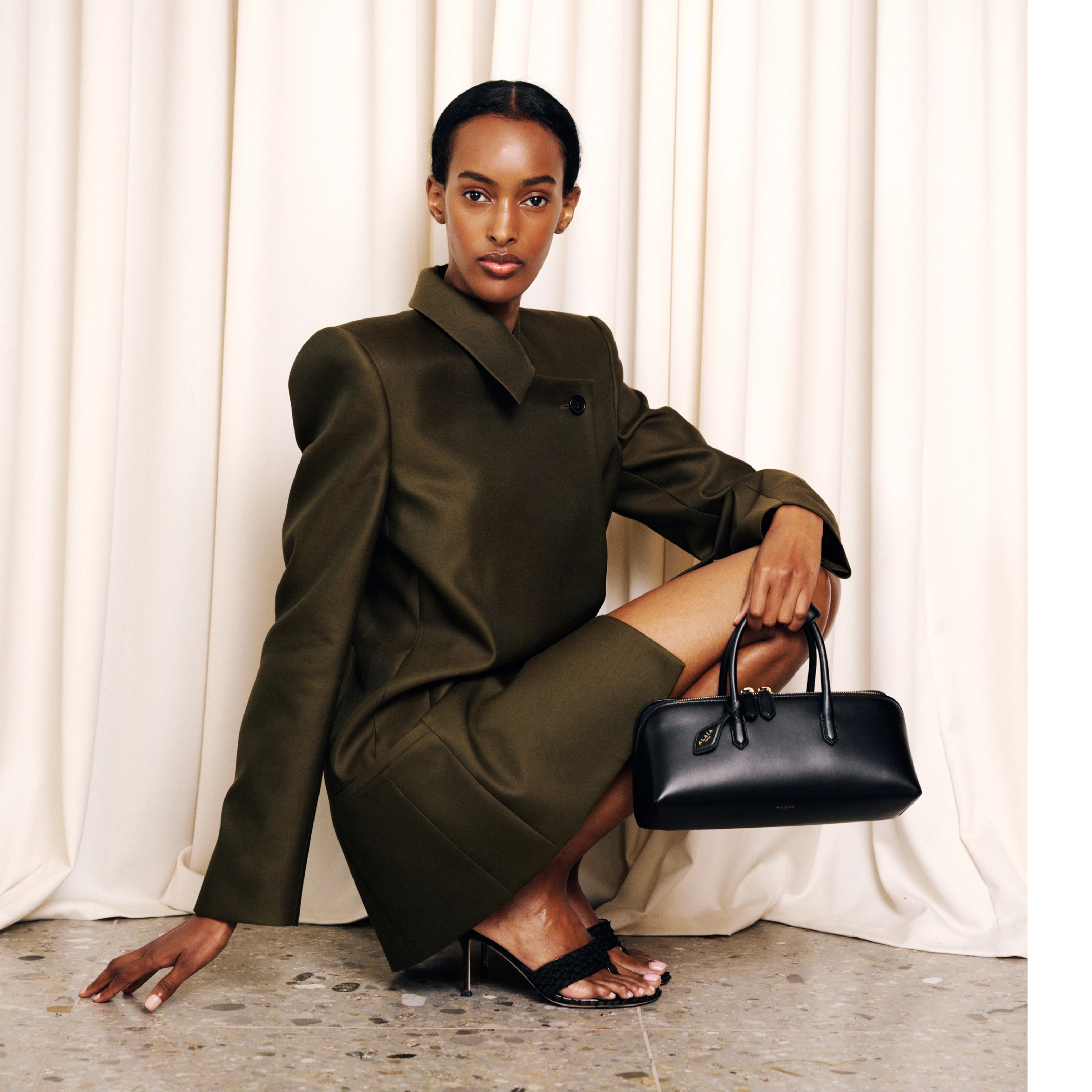 Image 3 of 3 - BLACK - Alaa Women's Delta Small Bag In Box Calfskin features a sculptural sihlouette crafted from soft box calfskin leather and features an elongated silhouette with clean square lines, top handles, a double zip closure, and a front gusset compartment for organized storage. Finished with a decorative branded tie and designed for hand carry. Main Material: 100% Calf Leather. Dimensions: 28 x 11 x 10 cm. Fits a large phone, card case, keys, sunglasses and other small essentials. Made in Italy.