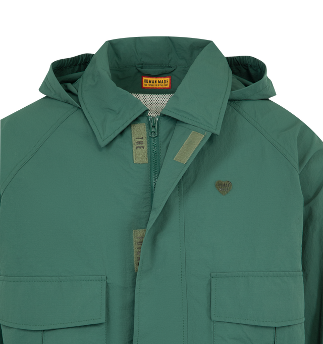 Image 4 of 4 - GREEN - HUMAN MADE Fishing Jacket featuring boxy silhouette, medium-weight nylon ripstop material, mesh lining, back vent reduces heat buildup for extra comfort, back graphic combines a polar bear patch and logo print, logo magic tape on the left chest, sleeve tabs and pocket flaps, hem drawcord with heart stoppers and packable hood stored in the collar. 100% nylon. Lining: 100% polyester.